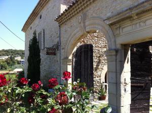 un edificio de piedra con rosas rojas delante de él en Le Mas de la Roche, en Montbrison-sur-Lez