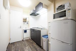 una pequeña cocina con electrodomésticos blancos y suelo de madera. en GOEN inn Tokyo, en Tokio