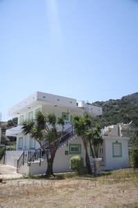 a white house with palm trees in front of it at Kleanthis Apartments in Rodakino