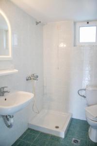 La salle de bains blanche est pourvue d'un lavabo et de toilettes. dans l'établissement Kleanthis Apartments, à Rodakino