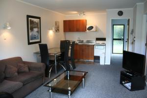 a living room with a couch and a table and a kitchen at Awatea Park Motel in Palmerston North