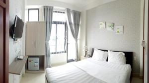a bedroom with a white bed and a window at Tin Tin Hue Hostel in Hue