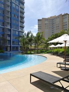 a swimming pool with chairs and umbrellas and buildings at BLU-Pool Access in Cha Am