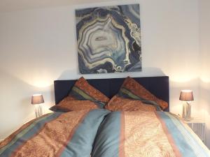 Un dormitorio con una cama con una pintura encima. en Tami's Harzglück, en Braunlage