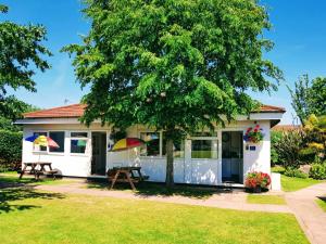 a cottage with a picnic table and a tree at Dawlish Warren Holidays in Dawlish
