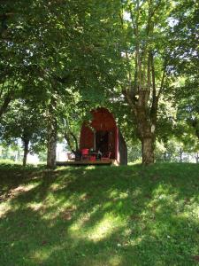 a small red tent in a field with trees at Les Cahutes d'Olt in Saint-Laurent-dʼOlt