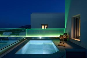 una casa con piscina di notte di Ikies Santo Filoxenia Apartments a Karterados