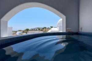 a swimming pool in a building with an archway at Ikies Santo Filoxenia Apartments in Karterados