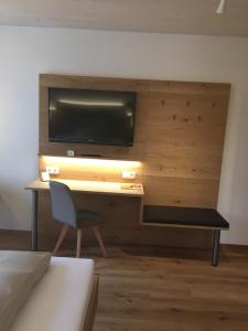 Schlafzimmer mit einem Schreibtisch, einem TV und einem Stuhl in der Unterkunft Landgasthof zum Muller in Ruderting