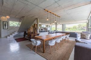 a dining room and living room with a wooden table and chairs at Red Box Villa in Plettenberg Bay