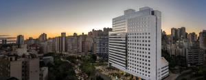 Intercity Porto Alegre Cidade Baixa في بورتو أليغري: مبنى أبيض طويل في مدينة عند غروب الشمس