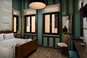 ハニア・タウンにあるNonnalena Boutique Hotelの緑の壁のベッドルーム1室、ベッド1台、椅子1脚が備わります。
