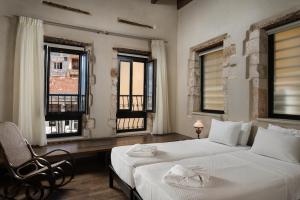 a bedroom with two beds and a chair and windows at Nonnalena Boutique Hotel in Chania Town