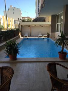 a swimming pool with two chairs and a table and two plants at Vesta Apart Hotel in Kuşadası