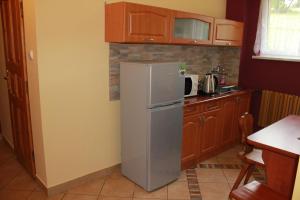 a kitchen with a refrigerator and wooden cabinets at Ośrodek Wczasowy Panorama in Bukowina Tatrzańska