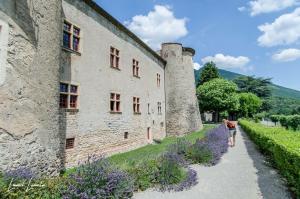 a woman walking past a castle with purple flowers at Camping Mon Repos in Montmaur