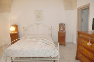 een slaapkamer met een wit bed en een houten dressoir bij Sottacastieddu in Avetrana