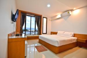 Sabuy Best Hotel Phayao في فاياو: غرفة نوم بسرير وتلفزيون ونافذة