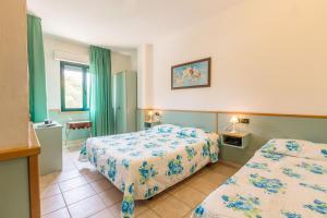 アッシジにあるHotel Franco Antonelliのベッド2台と緑のカーテンが備わるホテルルームです。