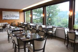 a dining room with tables and chairs and large windows at Haus am Wald in Eltmann