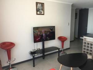 een kamer met een flatscreen-tv aan een muur met rode krukken bij Apartment Joet La Herradura in Coquimbo