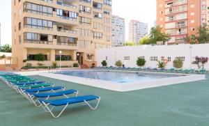 basen z niebieskimi leżakami obok budynku w obiekcie Gemelos 4 - Beninter All Inclusive w mieście Benidorm