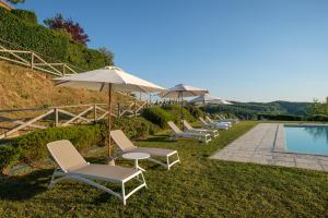 een rij stoelen en parasols naast een zwembad bij Borgo Amarrante in Montaione