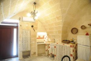 a kitchen with a stone wall with a chandelier at Palazzo Savoia 1856 in Fasano