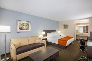 a hotel room with a bed and a couch at Days Inn & Suites by Wyndham Orlando Airport in Orlando +29 photos