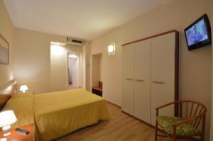 a bedroom with a bed and a chair and a tv at Hotel Genova in La Spezia