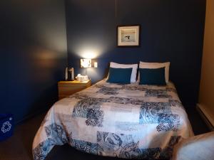 a bedroom with a large bed with blue walls at Motel de l'Anse a l'Eau in Tadoussac