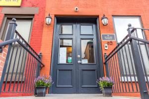 una puerta negra en un edificio de ladrillo con flores en The Park Ave North en Nueva York