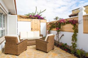 eine Terrasse mit Korbstühlen und Blumen in der Unterkunft Villa Veronica in Corralejo