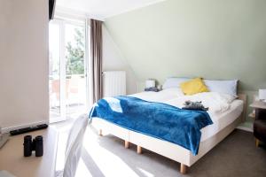 a bedroom with a bed with a blue blanket on it at Hotel Jess am Meer in Büsum