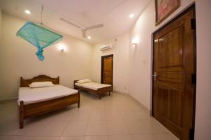 a small room with two beds and a door at First House Mihintale in Mihintale