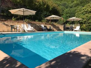 a blue swimming pool with chairs and umbrellas at Podere Montestuccioli in Cutigliano