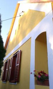 a yellow and white building with windows and flowers at Döröcske Vendégház in Somogydöröcske