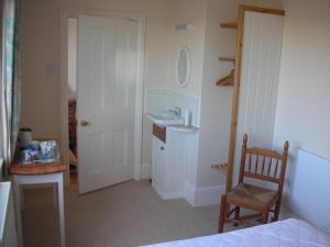 a bathroom with a sink and a mirror and a chair at The Cockatrice B&B in Reedham