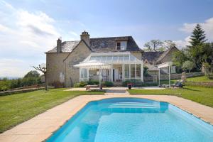 an estate with a swimming pool in front of a house at La Source Gilhodes in Castelnau-de-Mandailles