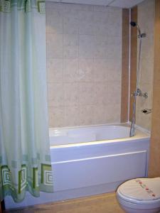 a bathroom with a tub and a toilet and a shower curtain at Hotel Restaurant Vodenitsata in Berkovitsa