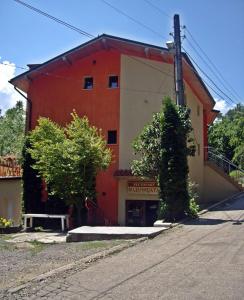 un bâtiment rouge et blanc avec un banc devant lui dans l'établissement Hotel Restaurant Vodenitsata, à Berkovitsa