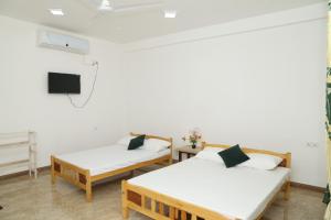 a room with two beds and a flat screen tv at Nilaveli Star View Hotel in Nilaveli
