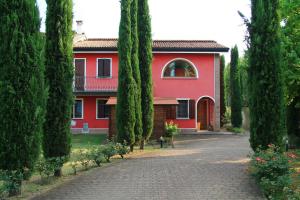 a red house with trees in front of it at La Luce della Luna in Castelnovo Bariano