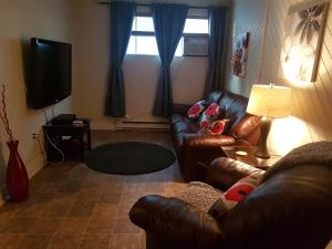 a living room with a leather couch and a television at 1-Bedroom Apartment Sweet #3 by Amazing Property Rentals in Gatineau
