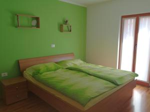 a green bedroom with a bed with a green comforter at Hiša Kranjc in Kobarid