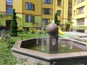 a fountain in front of a building with a playground at Apartments on Shashkevycha, 16 in Truskavets