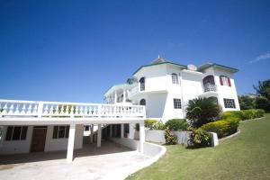 a large white house with a balcony and a yard at Sea View Chateau in Montego Bay