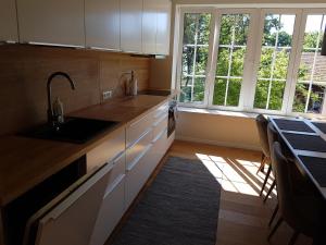 Una cocina con gabinetes blancos y un fregadero y una ventana. en Amber Wind Apartment, en Juodkrantė