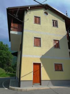 a yellow building with a door and windows at Hiša Kranjc in Kobarid