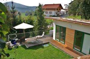 a deck with a chair and an umbrella on a house at BIO Appartement Resort in Bodenmais